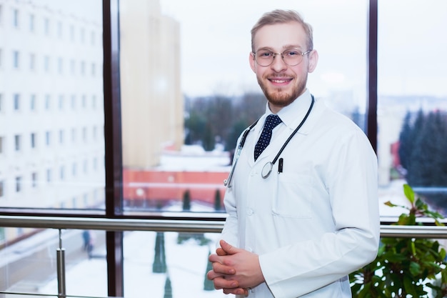 Médecin souriant et confiant à la réception, personnel médical travaillant en arrière-plan