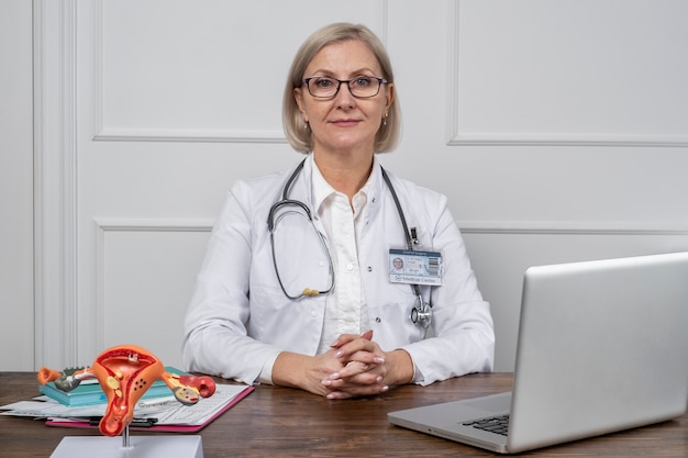 Photo médecin souriant à coup moyen assis au bureau