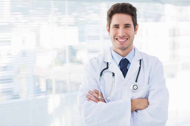 Médecin souriant croise les bras et regarde la caméra