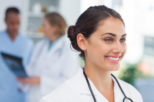 Médecin souriant, debout devant une équipe médicale