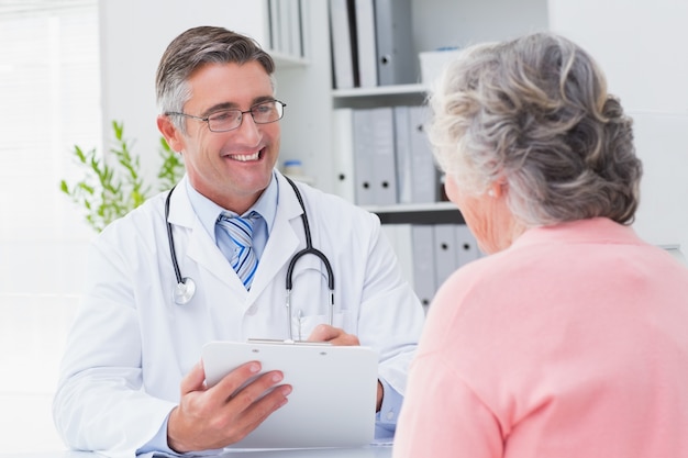 Médecin souriant, écrit des prescriptions pour le patient