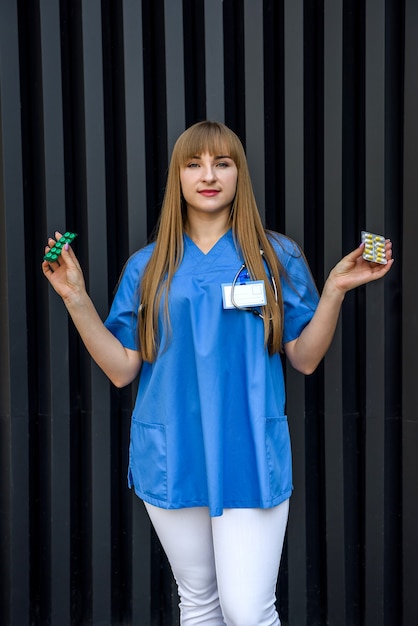 Médecin souriant offrant des pilules sous blister. Femme portant un uniforme médical et des gants de protection