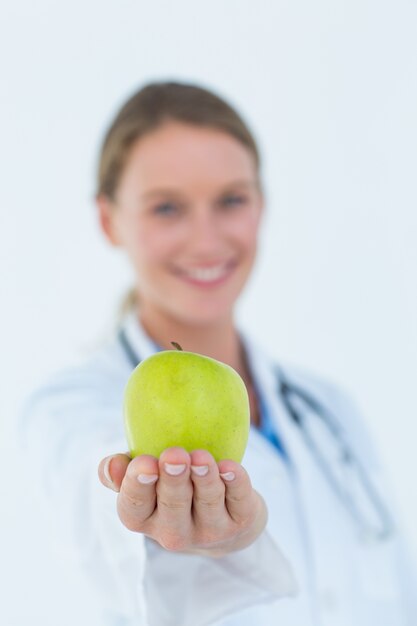 Médecin souriant offrant une pomme