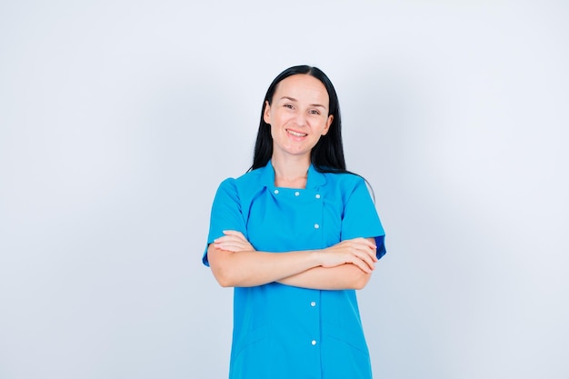 Un médecin souriant regarde la caméra en croisant les bras sur fond blanc