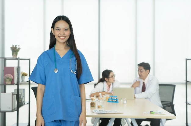 Un médecin souriant se tient devant la réunion de l'équipe médicale à l'arrière-plan