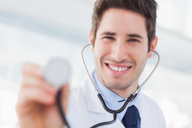 Médecin souriant avec son stéthoscope en regardant la caméra