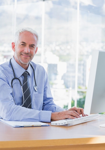 Médecin souriant, tapant sur son ordinateur