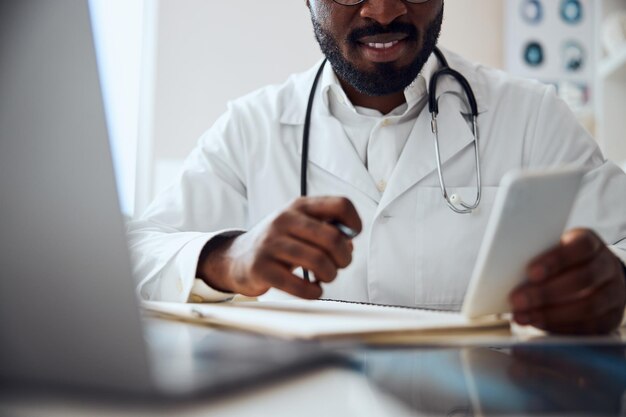 Un médecin souriant utilise un smartphone