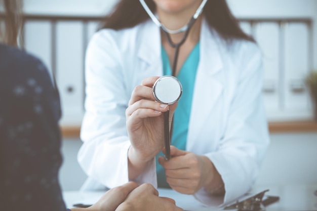 Médecin avec un stéthoscope à la main. Le médecin est prêt à examiner sa patiente.