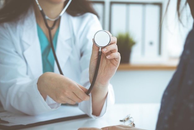 Médecin avec un stéthoscope à la main. Le médecin est prêt à examiner sa patiente.