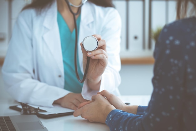 Médecin avec un stéthoscope à la main. Le médecin est prêt à examiner sa patiente.