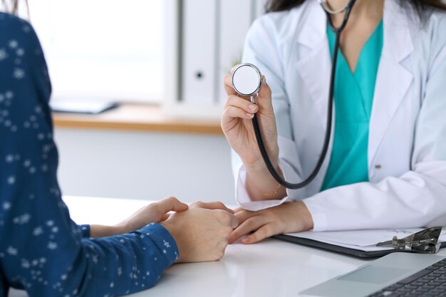 Médecin avec un stéthoscope à la main. Le médecin est prêt à examiner sa patiente.