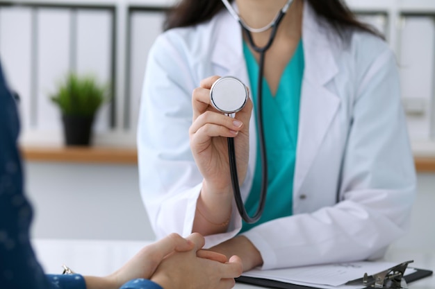 Médecin avec un stéthoscope à la main. Le médecin est prêt à examiner sa patiente.