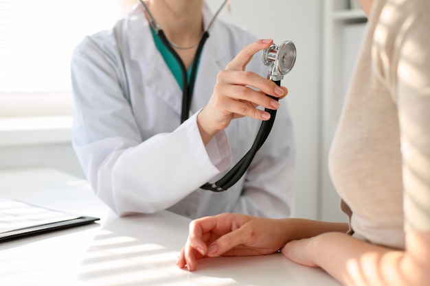 Médecin avec un stéthoscope à la main Le médecin examine sa patiente