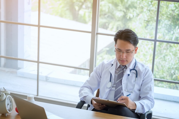 Médecin avec stéthoscope travaillant écrit sur la paperasserie