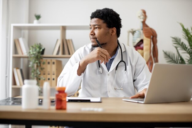 Médecin tapant sur un ordinateur portable et prenant des notes à la clinique