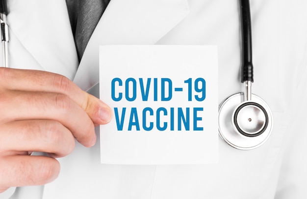 Médecin tenant une carte avec texte Vaccin Covid 19, concept médical