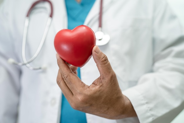 Médecin tenant un coeur rouge dans la salle d'hôpital concept médical solide et sain