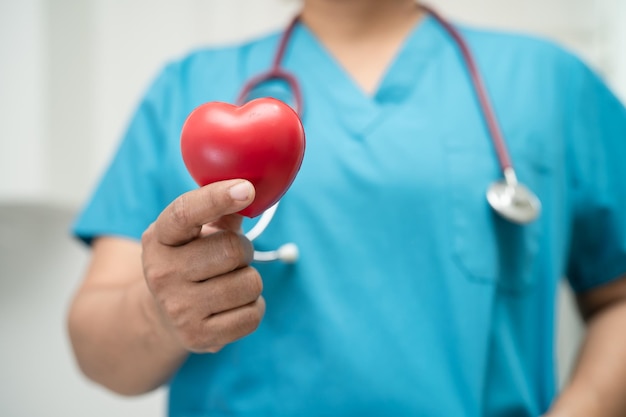 Médecin tenant un coeur rouge dans la salle d'hôpital concept médical solide et sain