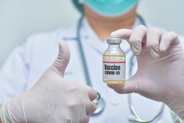 Médecin tenant le flacon de vaccin Covid-19-Médecine et montrant les pouces vers le haut.-recherche pharmaceutique et concept de soins de santé.