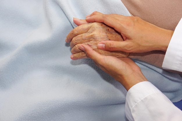 Le médecin tenant la main d'une patiente âgée ou d'une vieille dame âgée et l'encourage à l'hôpital