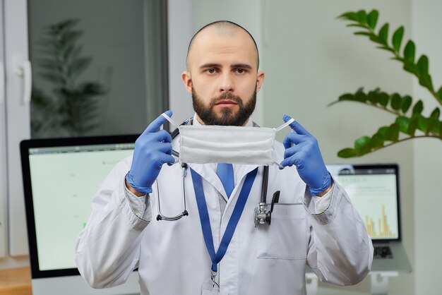 Un médecin tenant un masque protecteur pour éviter la propagation du coronavirus (COVID-19) dans son bureau.