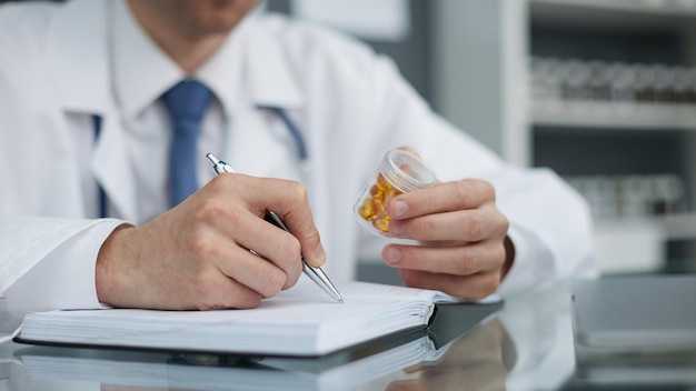Médecin tenant des pilules et prenant des notes dans un cahier
