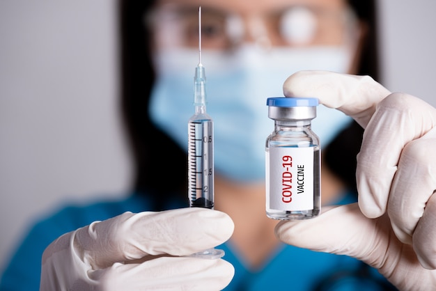 Médecin tenant une seringue et un vaccin COVID-19.