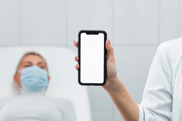 Photo médecin tenant un téléphone vide à côté du patient