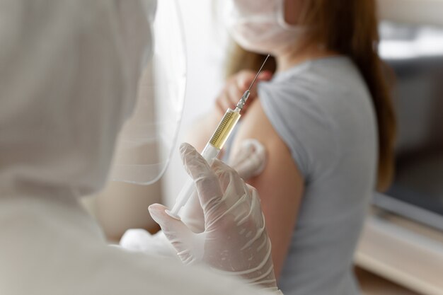 Médecin en tenue de protection individuelle ou EPI injecter le vaccin injecté pour stimuler l'immunité d'une patiente à risque d'infection par un coronavirus. Coronavirus, covid-19 et concept de vaccination