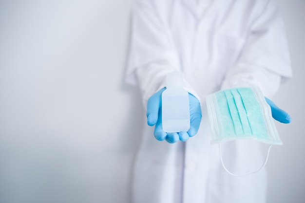 Photo le médecin tient un gel d'alcool et un masque facial