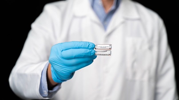 Photo un médecin tient le vaccin covid 19 contre le coronavirus dans sa main, un échantillon de sang infecté dans le tube à échantillon, un vaccin et une injection de seringue il est utilisé pour la prévention, l'immunisation et le traitement de covid-19