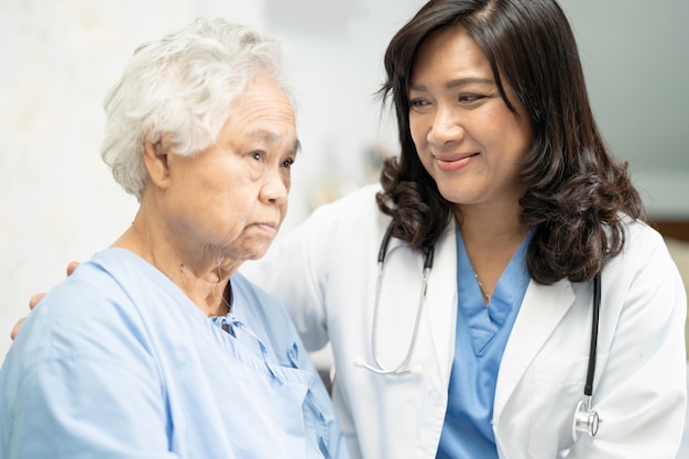 Médecin touchant une patiente asiatique senior avec amour.