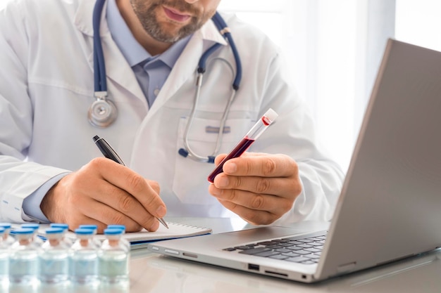 Médecin tout en travaillant dans son bureau, il est chargé de décrire un échantillon de sang dans un tube à essai