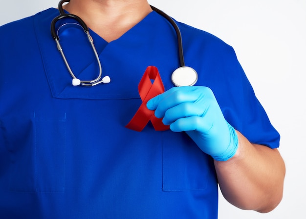 Médecin en uniforme bleu et gants en latex stériles est titulaire d'un ruban rouge