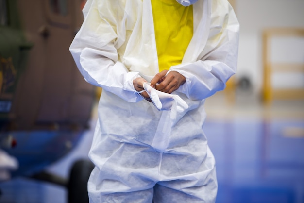 Médecin en uniforme EPI mettant des gants médicaux