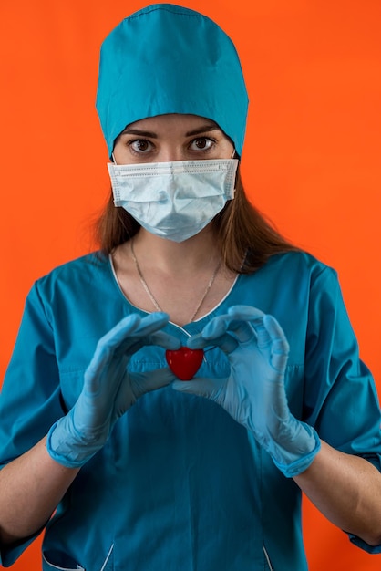 Médecin en uniforme en petit coeur rouge comme symbole dans la salle d'opération avec ses mains