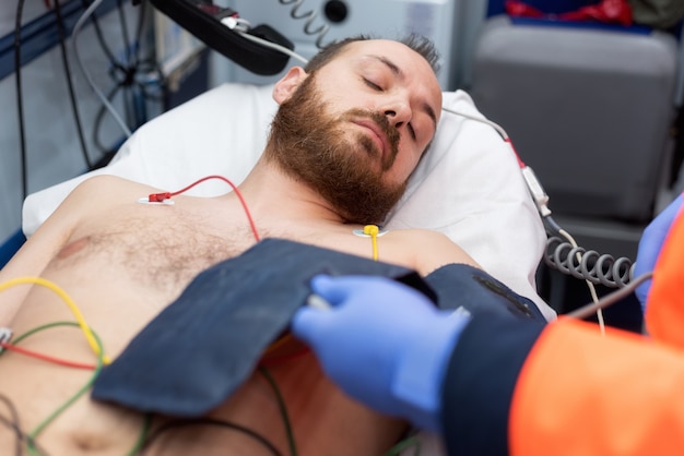 Photo médecin d'urgence vérifiant la pression artérielle d'un patient dans l'ambulance