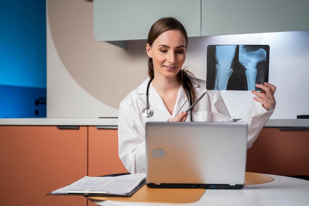 Une médecin utilisant un ordinateur portable, un appel vidéo en ligne, une conversation à distance avec un patient, une prescription de médicaments.