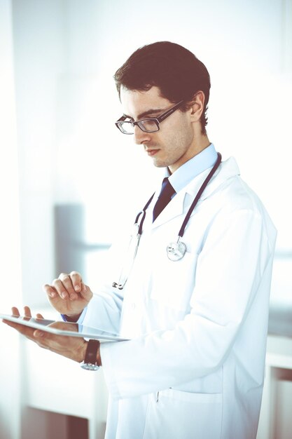 Médecin utilisant une tablette pour la recherche en réseau ou le traitement virtuel des maladies. Service médical parfait en clinique. Médecine moderne, données médicales et concepts de soins de santé.