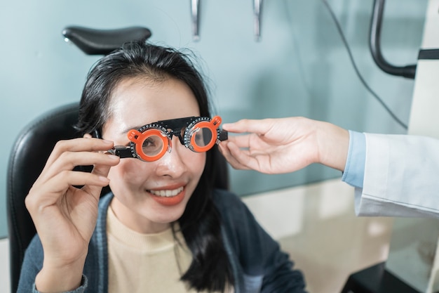 Un médecin utilise des lunettes de mesure pour une patiente dans une pièce d'une clinique ophtalmologique