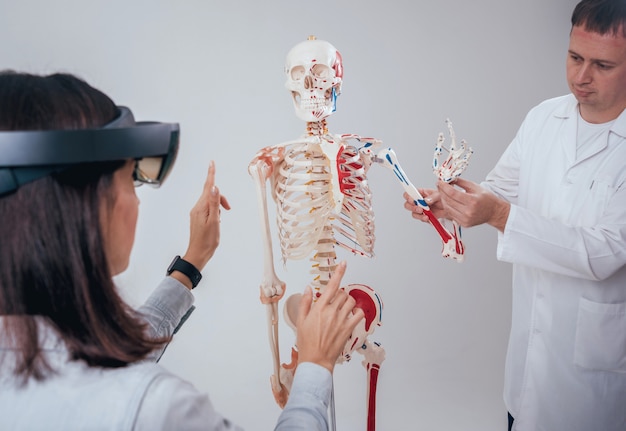 Photo un médecin utilise des lunettes de réalité augmentée et un squelette humain pour enseigner à un étudiant