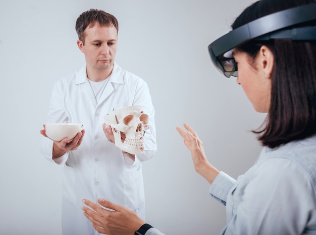 Photo un médecin utilise des lunettes de réalité augmentée et un squelette humain pour enseigner à un étudiant