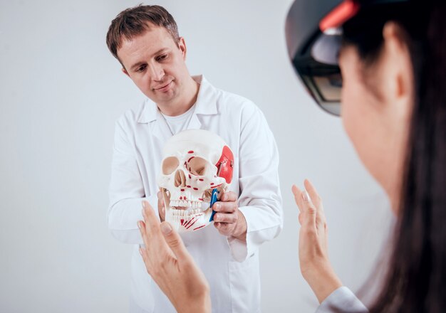 Un médecin utilise des lunettes de réalité augmentée et un squelette humain pour enseigner à un étudiant