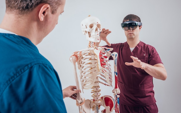 Photo un médecin utilise des lunettes de réalité augmentée et un squelette humain pour enseigner à un étudiant