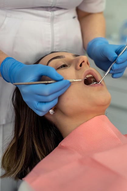 Le médecin utilise des outils dentaires pour vérifier la prévention des caries des dents et des gencives chez sa patiente