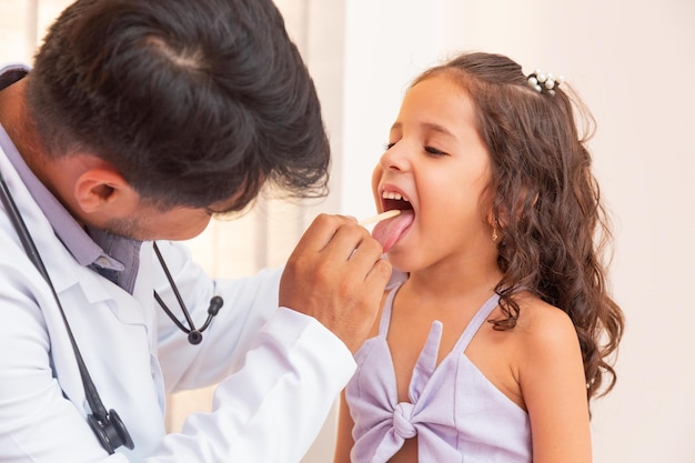 Médecin vérifiant la gorge de la petite fille. Fille avec mal de gorge en consultation avec la pédiatrie