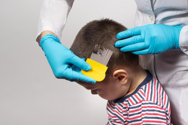 Le médecin vérifie la présence de poux chez un petit enfant à l'aide d'une crête