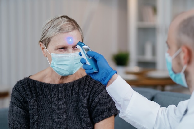 Le médecin vérifie la température du patient lors d'une visite à domicile