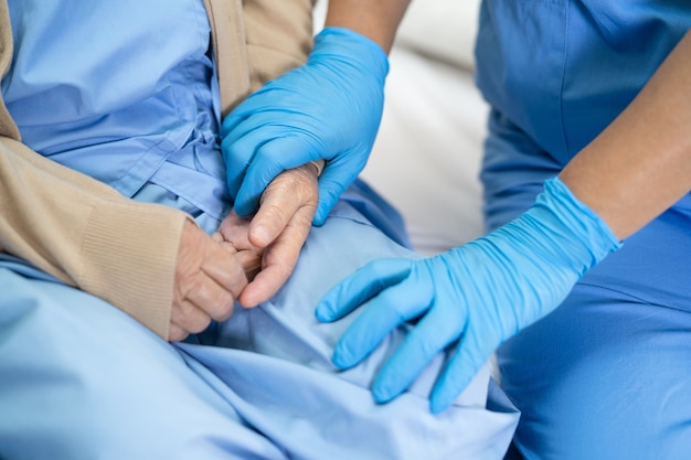 Le médecin vérifie et touche avec un gant Une patiente asiatique âgée ou âgée de vieille dame à l'hôpital pour protéger l'infection Covid-19 Coronavirus.